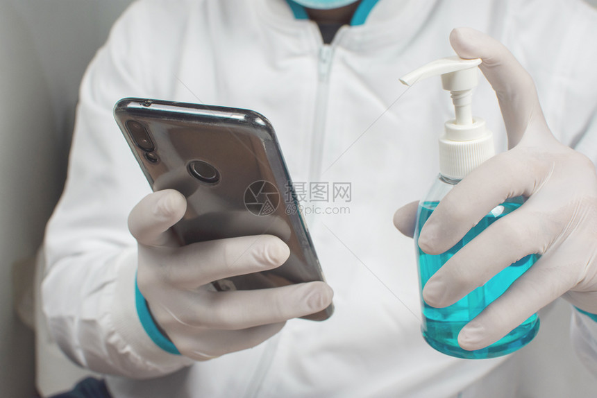 药物卫生Covid19预防手上的酒精消毒剂正在清洗智能手机以防感染Corona抗菌图片