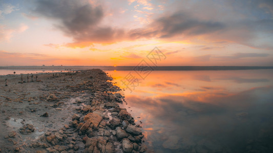 在日落时盐湖多彩的日落全景光线下干燥湖岸边水变暖图片