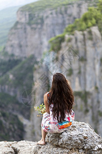 在峡谷抽烟的年轻女子地质学荒野攀登图片