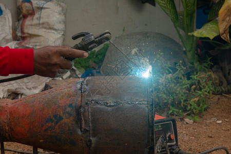 劳动建造焊接机正在施工地焊接金属管道技能的图片