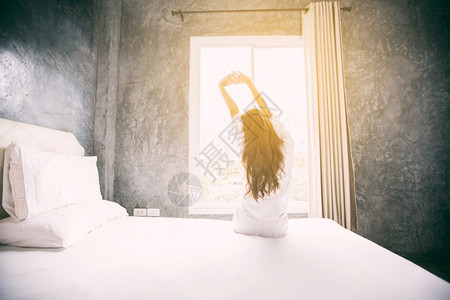 寝具说谎懒惰的在床上醒来亚裔女人完全休息早上打开窗帘呼吸新鲜空气图片