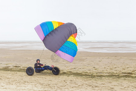 荷兰语白种男青少年驱动器风筝虫在有海的滩上放风筝传单冒险飞行图片