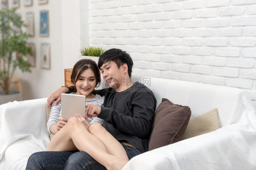 移动的日本人快乐亚洲爱坐着利用数字技术平板在现代家庭客厅沙发上自拍两者成功和生活方式概念一女士图片