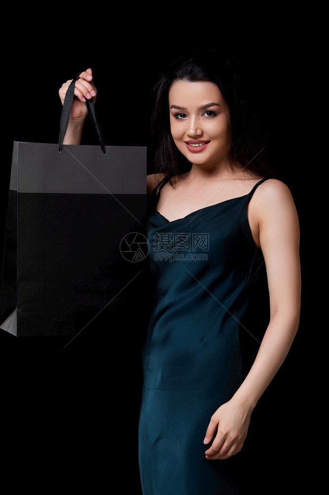 绿色身着深裙子的年轻美女手里拿着黑纸购物袋在色孤立的背景下被困在她手上广告包裹图片