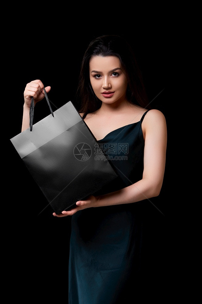 绿色购物者奢华身着深绿裙子的年轻美女手里拿着黑纸购物袋在色孤立的背景下被困在她手上图片