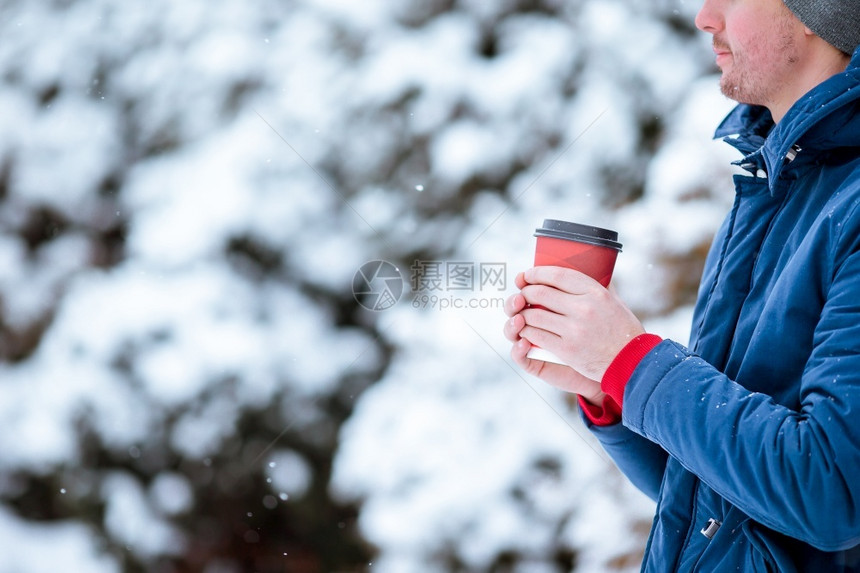 在寒冷的冬日户外喝咖啡的年轻caucasian男子快乐的人在冬天喝咖啡饮料时间店图片