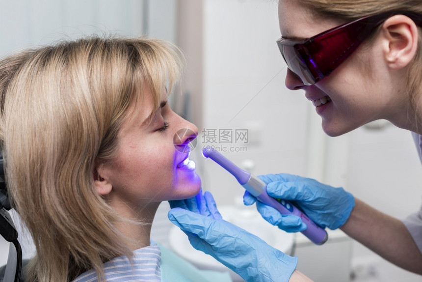 年轻的牙医进行齿美白考试药物图片