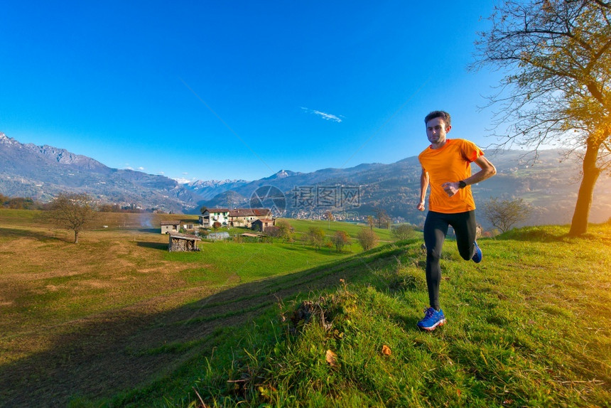 团队户外意大利阿尔卑斯山谷的落龙者在老村庄的上面草原奔跑积极的图片