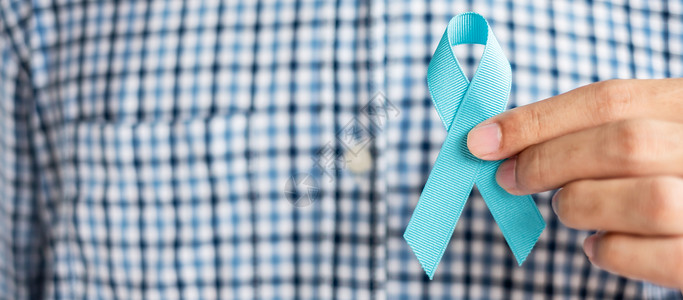 手拿蓝色丝带预防癌症概念图片