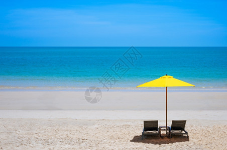 黄色的雨伞海滩天夏热带季沙滩在阳光明媚的日间长途旅行和暑假概念下用黄色雨伞蓝海背景和配有两张坐椅背景