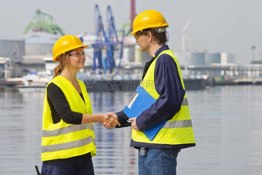 摇晃技术合作伙伴两个在工业港口互相打招呼的码头工人身着必要的安全装备穿着制服图片