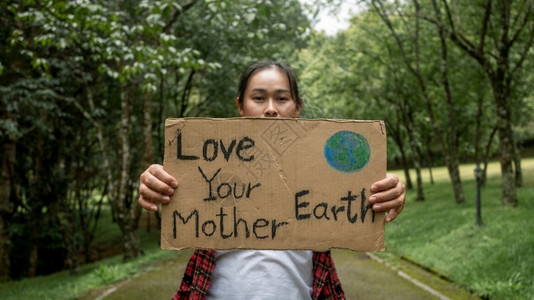 站立户外一名持有自然保护标志的女愿者在森林中属于自然界世环境日的概念是世界环境日的理念之一塑料图片