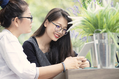 两个手拿着智能机的亚洲女人在客厅里说话面带快乐的脸庞女士肖像放松图片