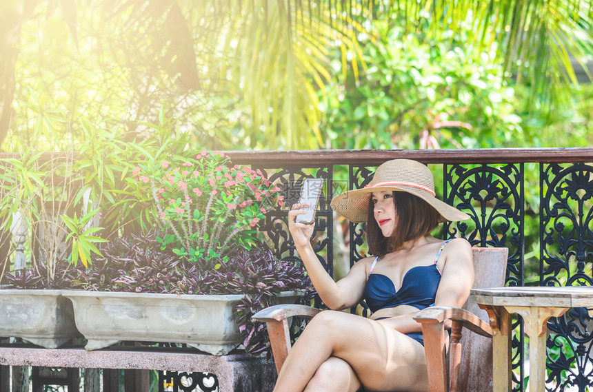美丽的游泳电话穿衣的感亚洲女人肖像智能手机图片