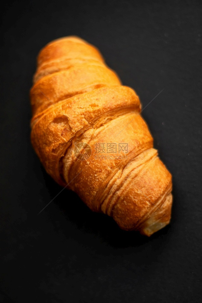 早餐棕色的桌子深背景中的新鲜出炉羊角面包深色背景中的新鲜羊角面包图片