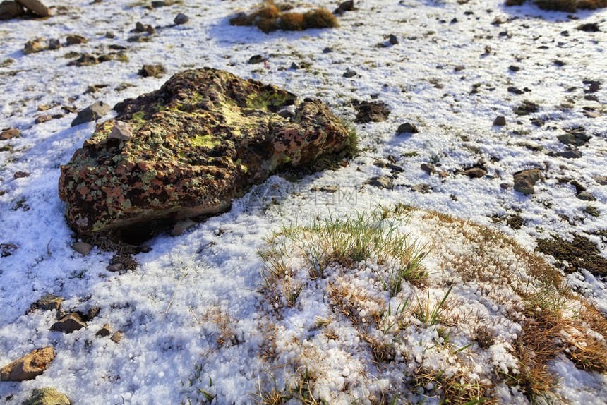 荒野清晨春天在土耳其中部山区的太阳升起光线上在土耳其中部山脉的大冰雹和石块风景中年轻草地和脊椎苔中的大冰雹和石头上的有目共睹的景图片