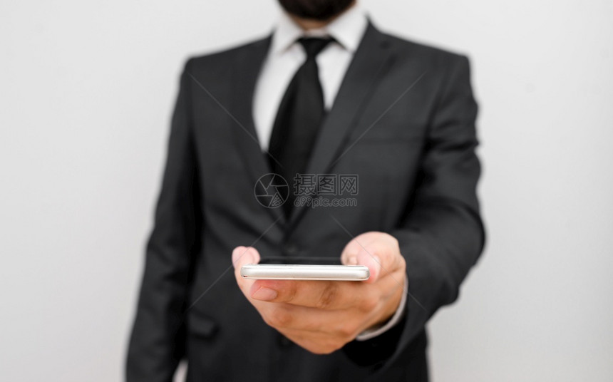 男穿正规工作服身着智能高科技手机持高科技手机用一只牵起小型移动高技术电话身着长胡子的男穿着正式工作服的人则佩戴高科技智能手机设备图片