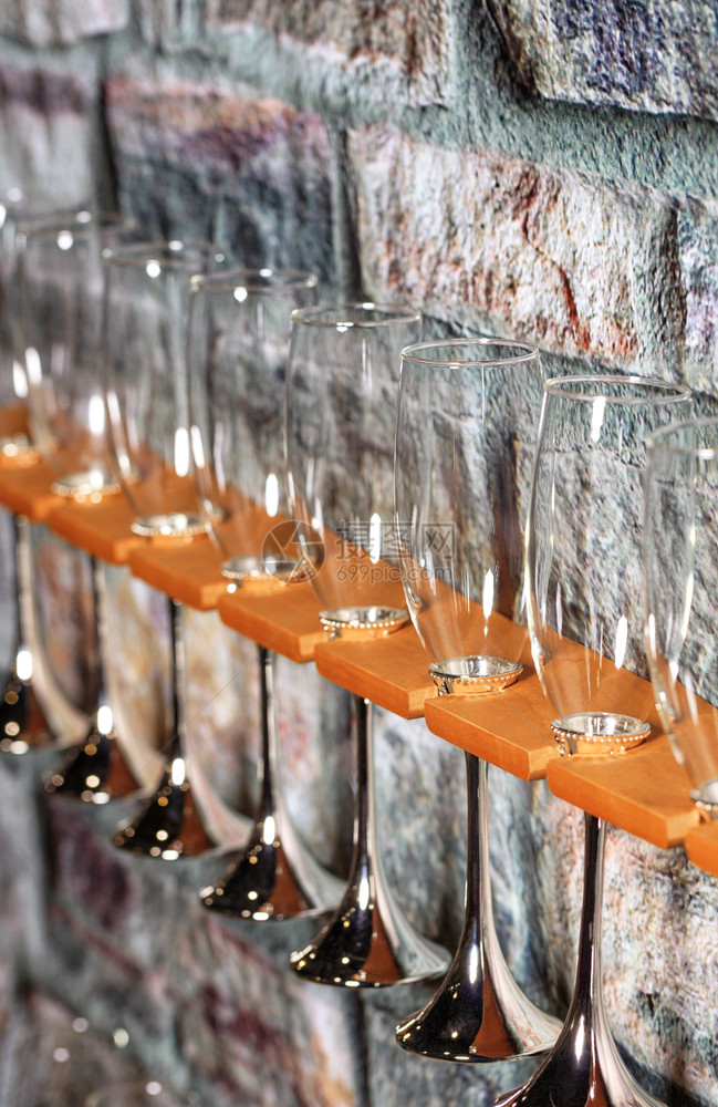 材料玻璃香槟杯放在一个架子的玻璃杯上紧靠一座旧石墙在块的背景上用玻璃香槟杯复制文本空间贮存哪里图片