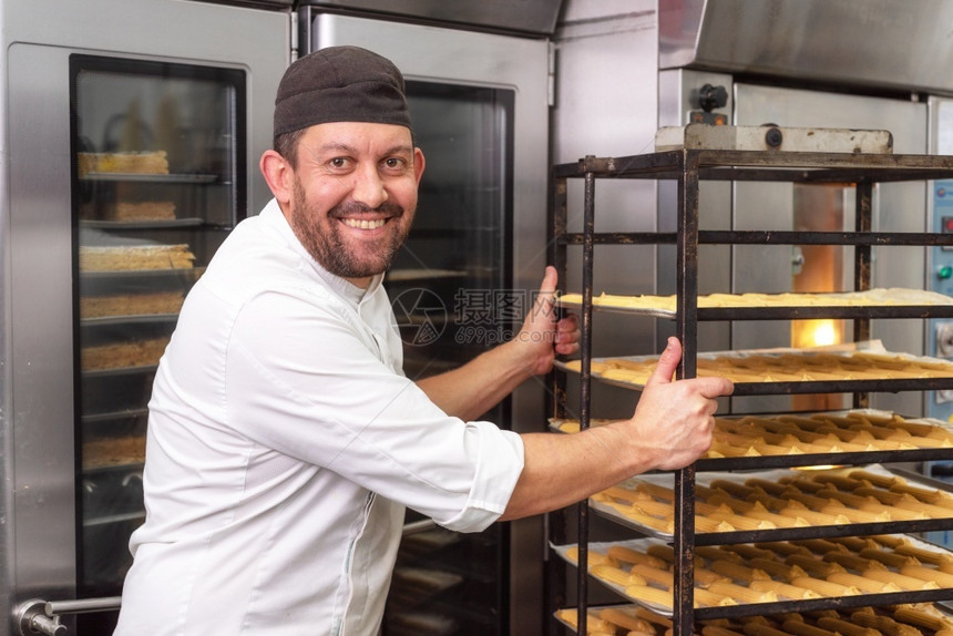 商业的可口贝克将一排糕点放入面包店或糕点的烤箱中贝克将一排糕点放入面包店或糕点的烤箱中产品图片