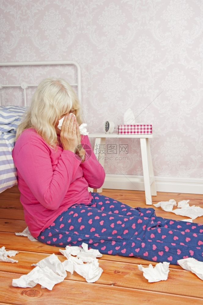 生病的身着粉色睡衣和纸巾躺在床边地板上的生病女情感痛图片
