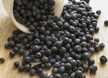 成熟从白蓝莓中散落的布在木头表面的白圆上从杯蓝莓洒到桌子上饮食浆果图片