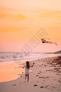 夕阳下的小女孩在海滩上放风筝图片