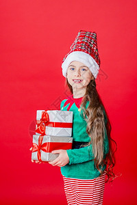 带礼物的精灵女孩亮红色背景上的圣诞老人助手一个美丽的精灵婴儿肖像复制空间带礼物的精灵女孩亮红色背景上的圣诞老人助手孩子克劳斯展示背景图片