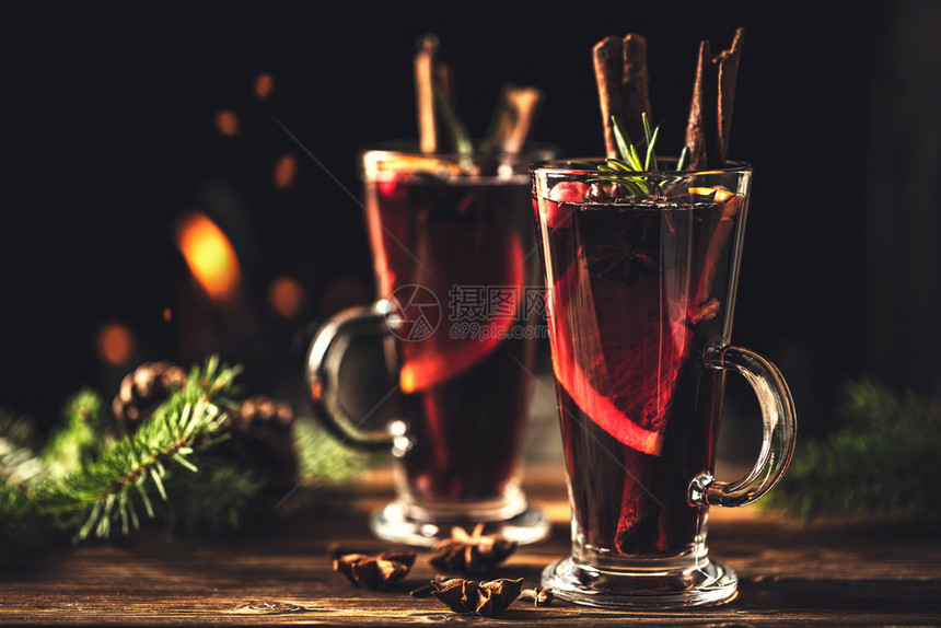 熟料在火炉灾的背景下在圣诞节假日传统冬季饮酒时木制桌上的边装有玻璃杯中调味品的混合葡萄酒橙祝贺图片