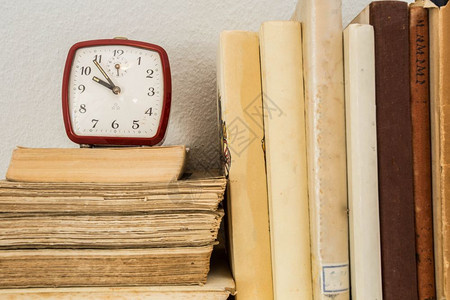 木制架子上的旧书和小时钟在小时钟木制架上学习收藏术的图片