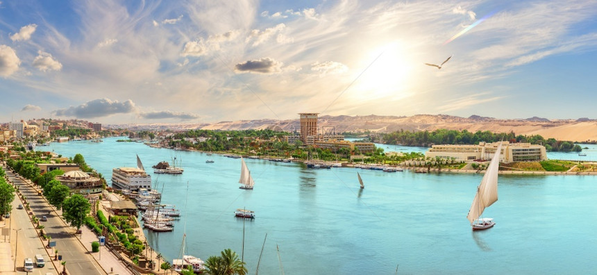 海岸游客美丽的尼罗河全景和有帆船的阿斯旺市埃及的美丽尼罗河全景和有帆船的阿苏纳市埃及天空图片