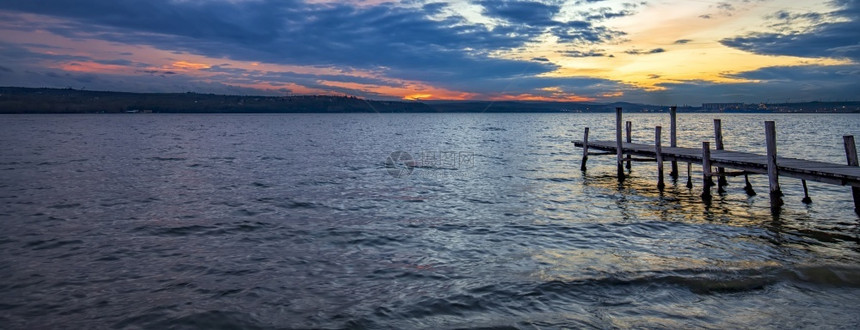 冷静的日落后带木头码的湖边海岸云丰富多彩的图片