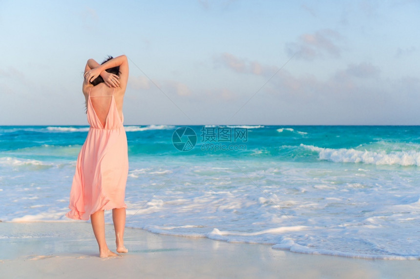 海滩上的年轻美女在海滩上度过暑假看着大海快乐的姑娘吃燕麦日落的后视镜躺在海滩上的女人自然数字孩图片