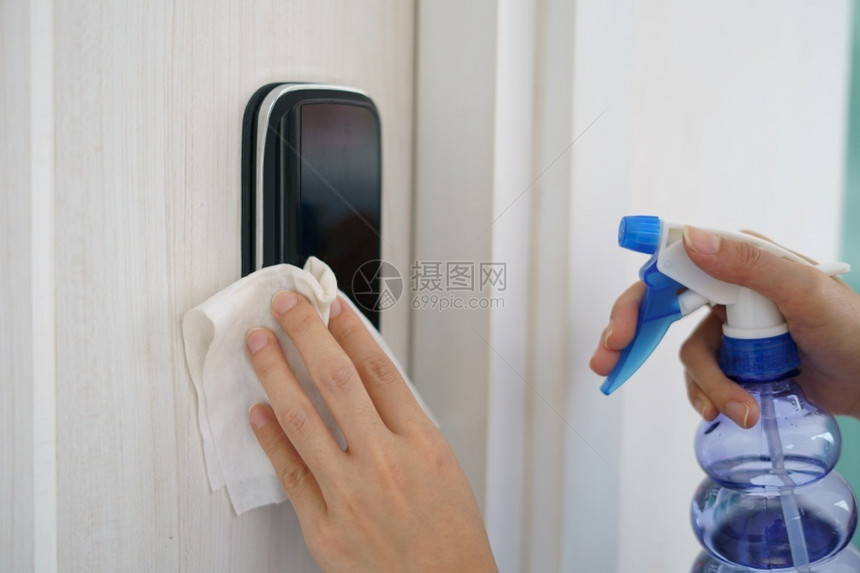 打扫女士工作手用餐巾纸和清洁剂喷洒门把手用于冠状菌或Covid19防护图片