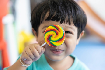 孩子墙一个穿绿衬衫的男孩正在享受着他多彩的圆棒糖图片