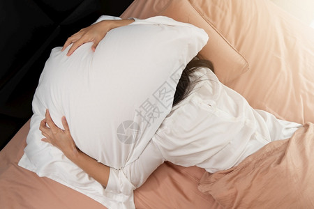 就寝时间钟睡不着的女人躲在枕头底下讨厌早上醒来的晨疲劳背景图片