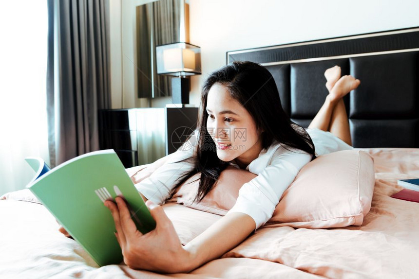 女人躺在床上看空书的白色亚洲羊毛图片