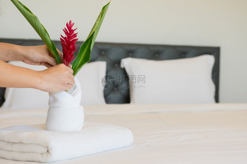 家政保持年轻的旅馆女青把软毛巾床铺和放在一家旅馆清洁工身上放在床干净的白毯子早卧室有枕头软毛巾采取图片
