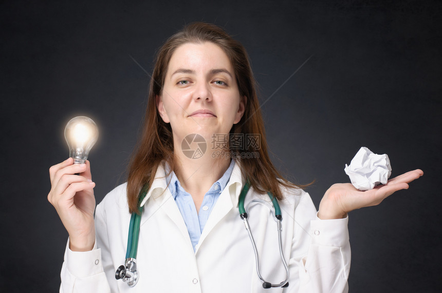 拥有发光灯泡和压碎纸的医生持有发光灯泡和压碎纸球的女医生发现疗的成功图片
