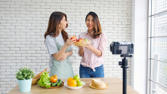 两位年轻的青女食物博客在录制视频时交谈与快乐刻vlog概念人与科技通讯等博主蔬菜朋友们背景图片