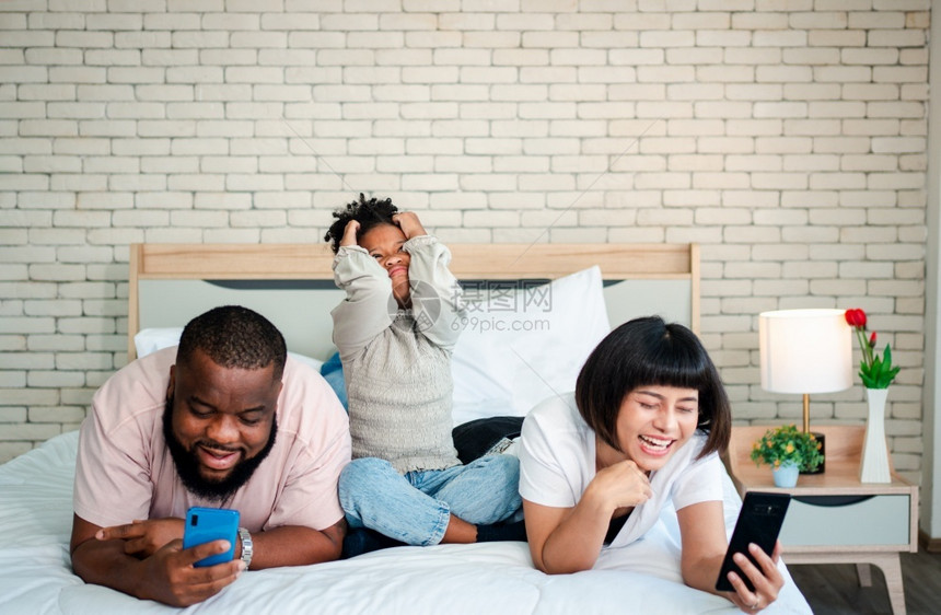 在床上看手机的一家人图片