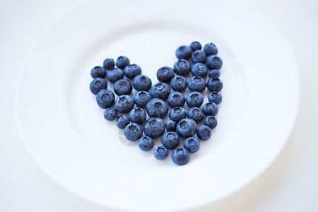 白盘上心形成熟蓝莓情人节卡片白盘上心形熟蓝莓桌子小吃甜的图片