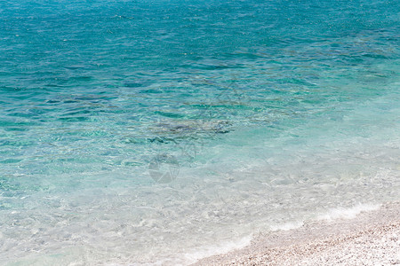 希腊语波浪PortoGermeno阿提卡希腊清澈的绿松石水岩海滩蓝色的背景图片