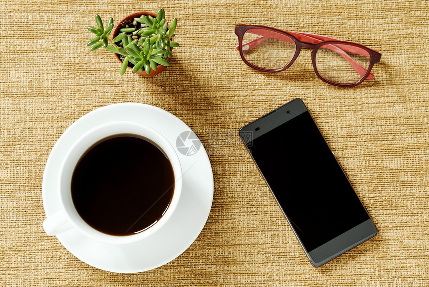 绿色空白的聪明顶端咖啡杯智能电话小绿树和棕色背景的眼镜图片