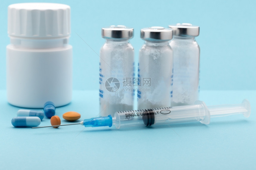 处方药店蓝色背景中的药丸瓶和注射器药丸瓶和注射器什锦的图片