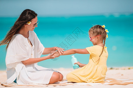 保护海洋孩子和母亲在沙滩边玩耍的小女孩背景