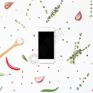 平板躺着迷迭香白色背景的智能手机模拟假冒空白文本间带绿色草药和香料菜单设计食品博客谱烹饪手册或配有素材的送餐程序背景图片