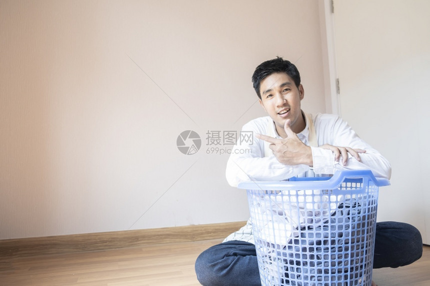 机器家务做庭作业的亚洲男子丈夫他正在准备篮子中的衣物用洗机服为家里的庭团聚提供各种生活方式服务微笑图片