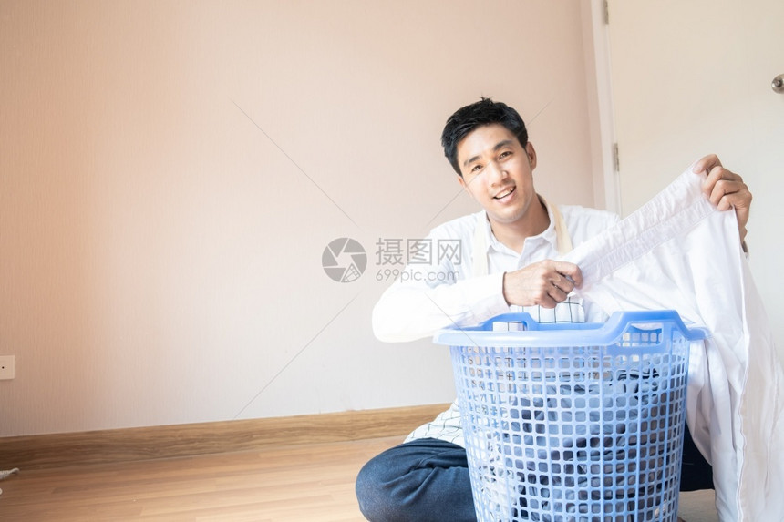 加载白种人国内的做家庭作业亚洲男子丈夫他正在准备篮子中的衣物用洗机服为家里的庭团聚提供各种生活方式服务图片