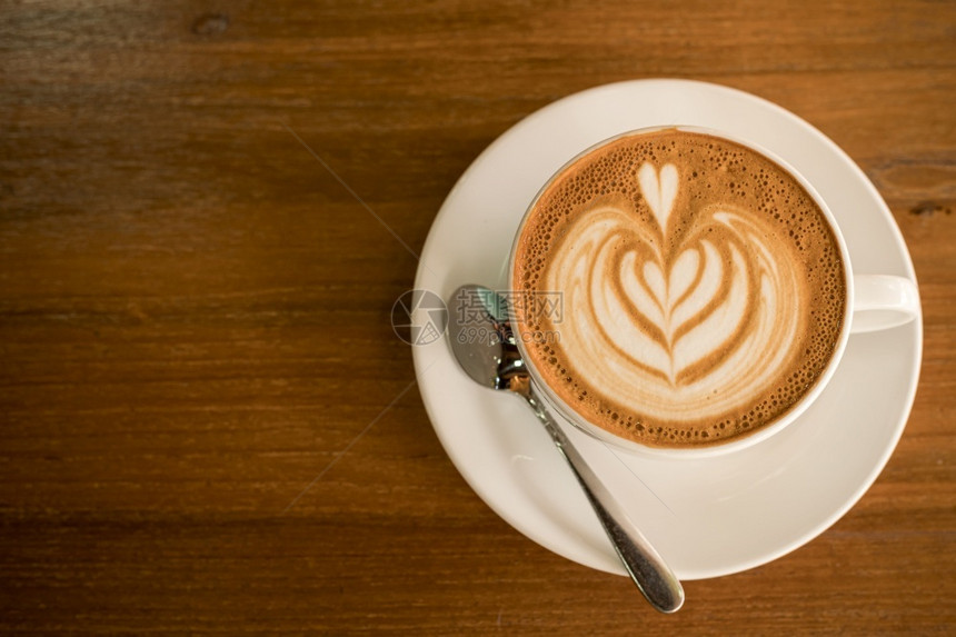 质地热咖啡拿铁和艺术牛奶泡沫杯放在最顶端的木桌前茶杯上在咖啡馆店吃早餐在商业工作构想期间早晨一种图片