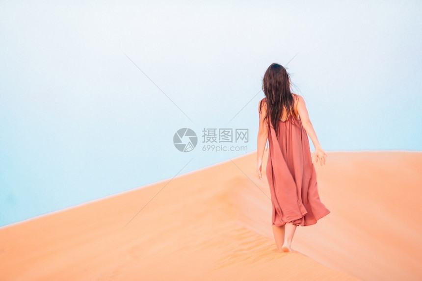 在阿拉伯联合酋长国沙漠中的丘美丽的女人在阿联酋最大沙漠中的丘晚上黄色的联合图片